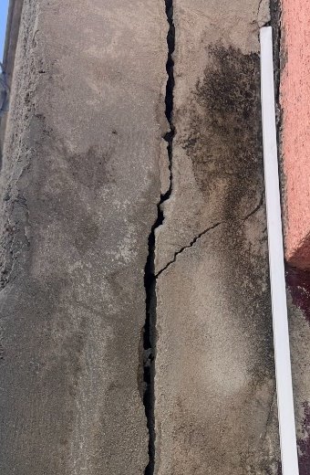 Recorte de contexto de uma fissura vertical visível em um muro